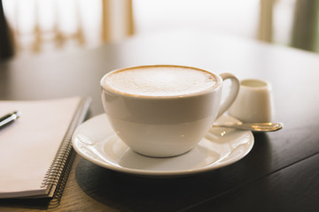 Cup of coffee , note and pen on wood table.