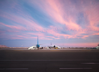 Fototapeta na wymiar View at airport and airplanes at sunset from the terminal