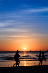 Obraz premium Silhouettes in front of a beautiful tropical sunset