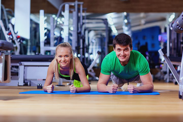 Sport couple doing pushups  bar on floor in the gym.