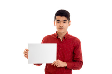 a young guy in a red shirt holding a white sheet of paper and looks into the camera