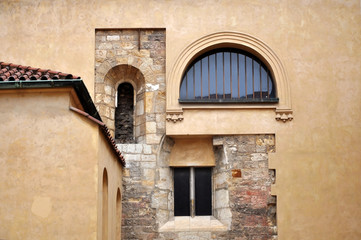 Fototapeta na wymiar Three windows of different shapes on beige stone wall. Prague, Czech Republic.