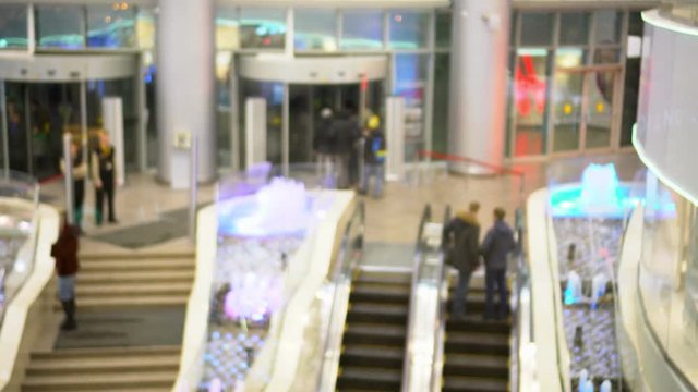 Shopping Center. People on escalators rise to an exit from shopping center and go down in it