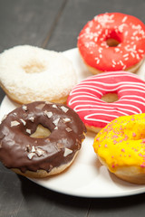 Colorful donuts on a black wooden background