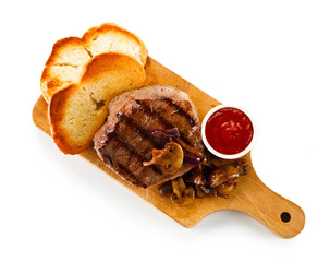 Grilled steak and toasts on wooden board