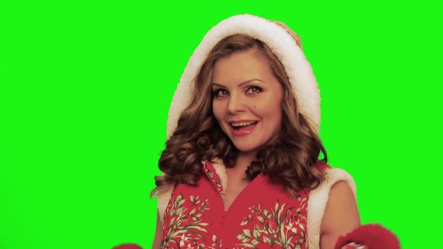 Pretty woman with curly hair wearing christmas costume and gloves and timbrel in her hands sings against chromakey.