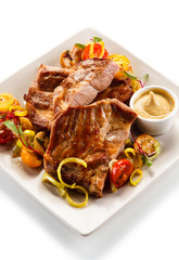 Roasted steaks with vegetables on white plate
