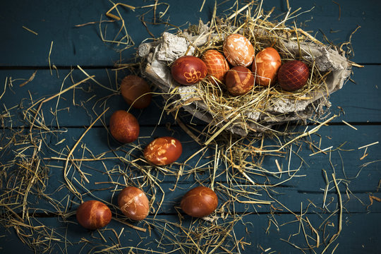 Ostereier (gefärbt mit Zwiebelschalen) in einem Nest auf blauen Holztisch