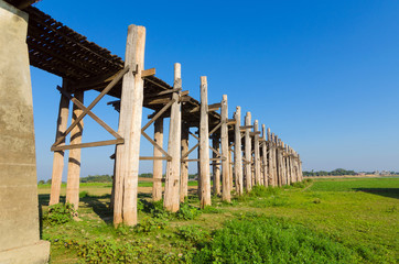 The longest bridge in the world with blue sky and green grass, U-Bein Bridge, Mandalay, Myanmar.