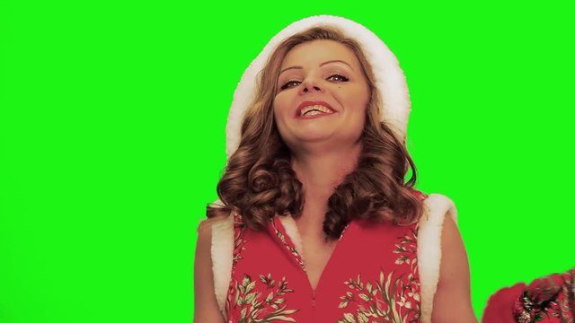 Pretty woman with curly hair wearing christmas costume and gloves and timbrel in her hands sings, laughs, forgets words, stops singing against chromakey.