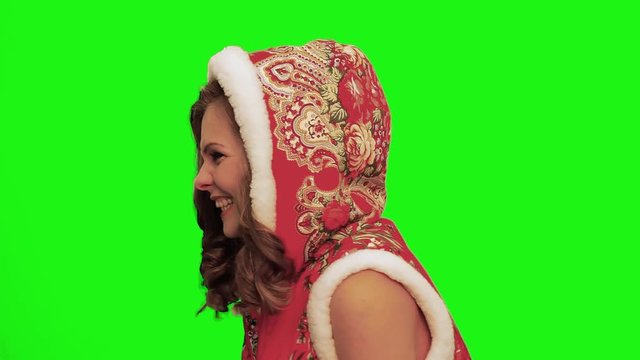 Pretty woman with curly hair wearing christmas costume and gloves and timbrel in her hands sings, laughs, forgets words, talks against chromakey.