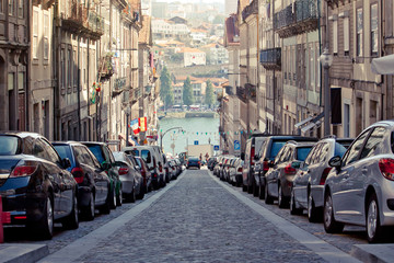 Perspective of old Porto street down to the river. Empty street with parking. Old European city. Portuguese real estate.