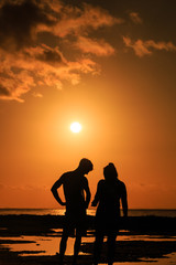 Fototapeta na wymiar A couple watching sunset over a tropical ocean