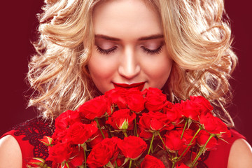 Beautiful blonde woman holding bouquet of red roses. International Women's Day, Eight March celebration.