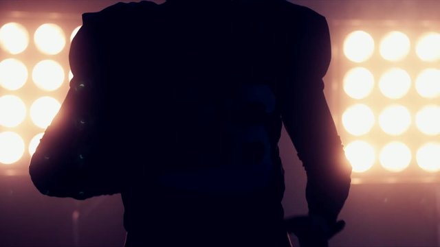 CU Silhouette of male American football player holding a ball in his hands against bright stadium illumination lights. 4K UHD RAW edited footage