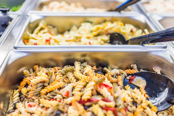 Macro closeup of different pasta salads in salad bar counter