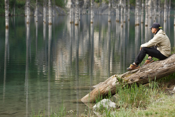 Fototapeta na wymiar Young man on the shore of a mountain lake