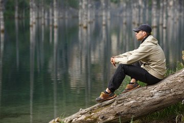 Young man on the shore of a mountain lake