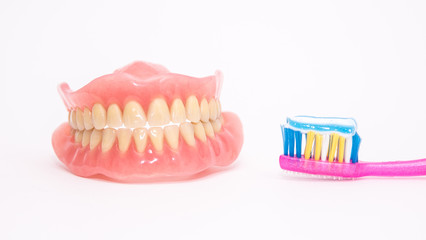 Two acrylic dentures ,toothbrush with toothpaste, white background.