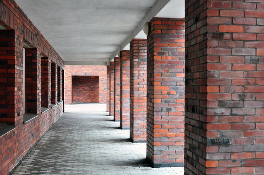 Architectural composition, exterior. Many red brick square columns and the wall in perspective.