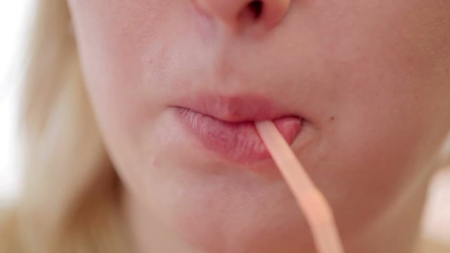 Young blonde woman drinking through straw closeup