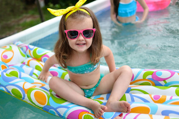 portrait of little girl in tropical style in a swimming pool