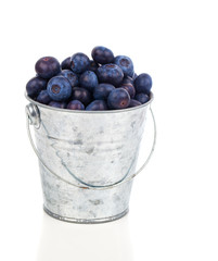 ripe blueberries in metallic bucket, on white background