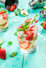Summer refreshing mojito cocktail with strawberry, mint and lime, on a light blue wooden table copy space