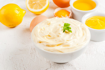 Mayonnaise with ingredients for cooking - eggs, vegetable oil, mustard, lemon, parsley. On the white stone concrete table copy space