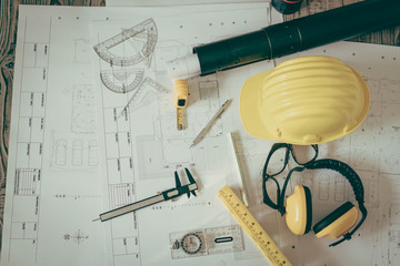 Construction plans with helmet and drawing tools on blueprints .  ( Filtered image processed...