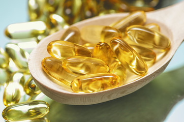 Closeup fish oil dietary supplement. Wooden spoon of oil fish capsules. Omega 3 pills fish oil capsules.