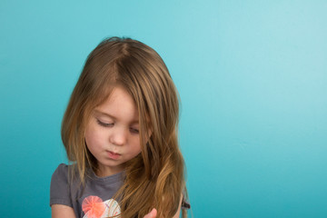 Sad little girl against teal background