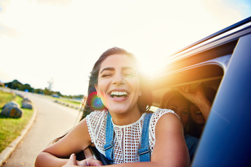 Pretty woman in speeding car smiles at camera