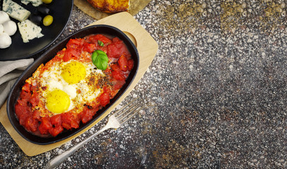 Two eggs with tomatoes, cheese, olives, orange juice and bread