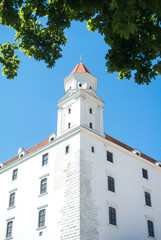 Close-up view to a tower of Bratislava castle and green maple leaves, Slovakia.