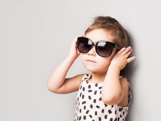 Naklejka premium Happy little girl with big sunglasses. Fashionable baby