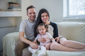 Happy young family of three sitting on the couch