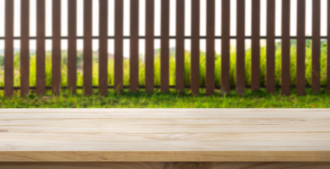 Wood table top with fence and grass in garden background.For  create product display or key visual layout
