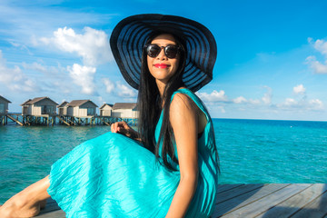 Portrait of happy young woman at beautiful water villa at Maldives island. Travel and Vacation. Outdoor shot.