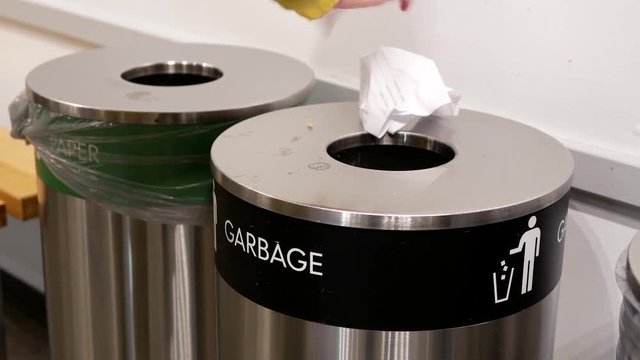 Woman throwing trash to the garbage can inside Ikea store