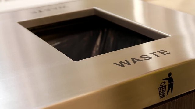 Woman throwing trash to the garbage can inside shopping mall