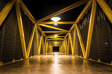 Yellow pedestrian bridge at night - some graffiti on the metal constructions