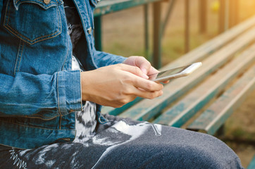 girl in jeans jacket using smart phonea