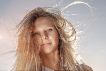 Young gender fluid person with long blond hair fly with the wind retro color sun flares