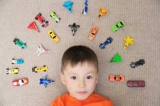 toddler boy playing with car collection on carpet. Transportation,airplane, plane and helicopter toys for children, miniature models.View from above. Many cars for little boys.