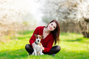 beautiful young woman sitting in front of wonderful blooming trees with her dog