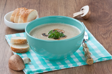 Mushroom soup / Creamy mushroom soup in blue bowl with fried mushrooms, parsley and white bread on wooden background 