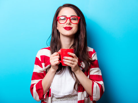 beautiful young woman with cup of coffee standing in front of wonderful blue background