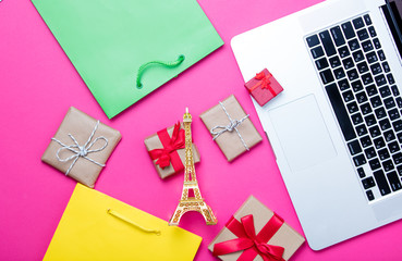 beautiful eiffel tower shaped toy, cute gifts, shopping bags and cool laptop on wonderful pink...
