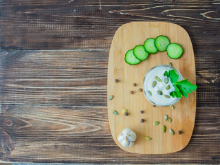 Homemade yogurt or a sour cream in a glass with fresh cucumber and parsley